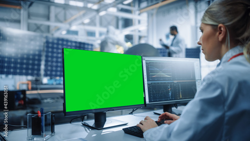 Female Engineer uses Green Screen Computer to Analyse Satellite. Aerospace Agency Manufacturing Facility: Scientists Develop, Assemble Spacecraft for Space Exploration Mission. Over Shoulder