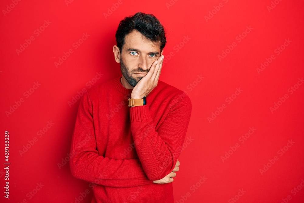 Handsome man with beard wearing casual red sweater thinking looking tired and bored with depression problems with crossed arms. Handsome man with beard wearing casual red sweater thinking looking tired and bored with depression problems with crossed arms.