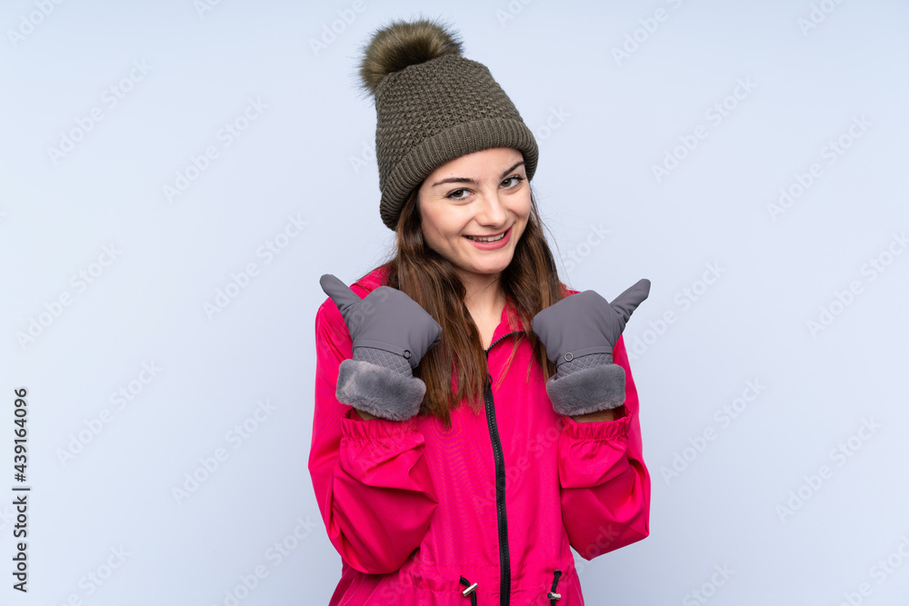 Young girl with winter hat isolated on blue background with thumbs up gesture and smiling Young girl with winter hat isolated on blue background with thumbs up gesture and smiling