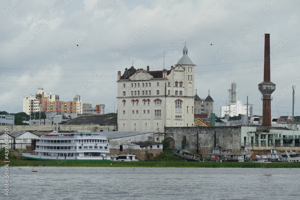 Obraz premium View over the branch of the Rio Negro river, the Iguarapé de Sao Raimundo to the historic old town with an abandoned former brewery building (Cervejeria). Manaus, Amazonas state, Brazil.