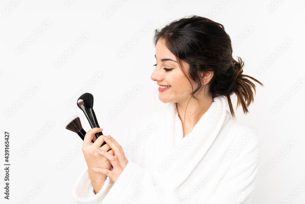 Young caucasian woman isolated on white background holding makeup brush and whit happy expression