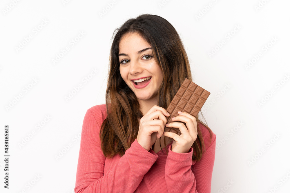 Young caucasian woman isolated on pink background taking a chocolate tablet and happy Young caucasian woman isolated on pink background taking a chocolate tablet and happy
