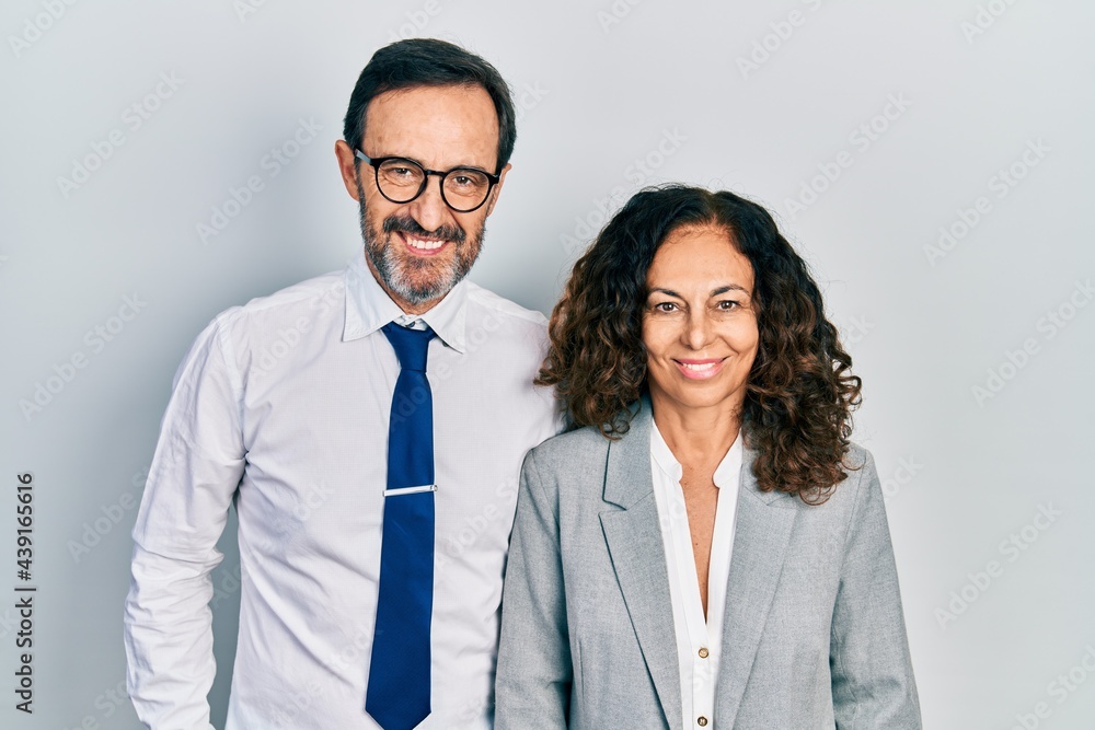 Middle age couple of hispanic woman and man wearing business office uniform with a happy and cool smile on face. lucky person. Middle age couple of hispanic woman and man wearing business office uniform with a happy and cool smile on face. lucky person.