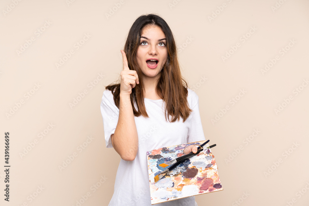 Young artist man holding a palette isolated on beige background pointing with the index finger a great idea Young artist man holding a palette isolated on beige background pointing with the index finger a great idea