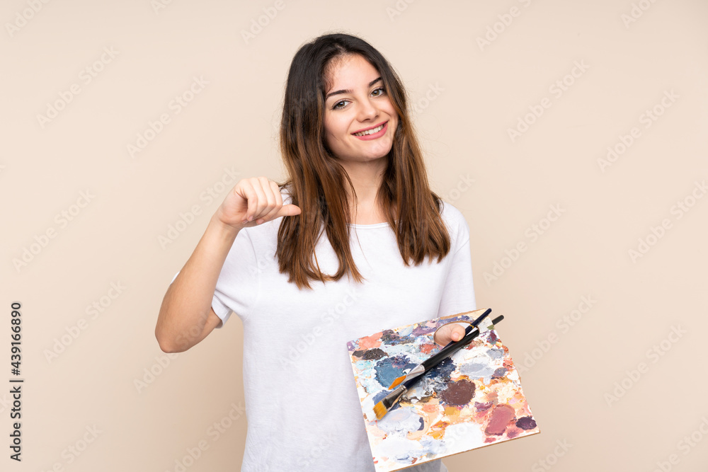 Young artist man holding a palette isolated on beige background proud and self-satisfied Young artist man holding a palette isolated on beige background proud and self-satisfied