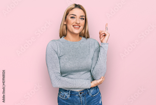 Young caucasian woman wearing casual clothes smiling happy pointing with hand and finger to the side