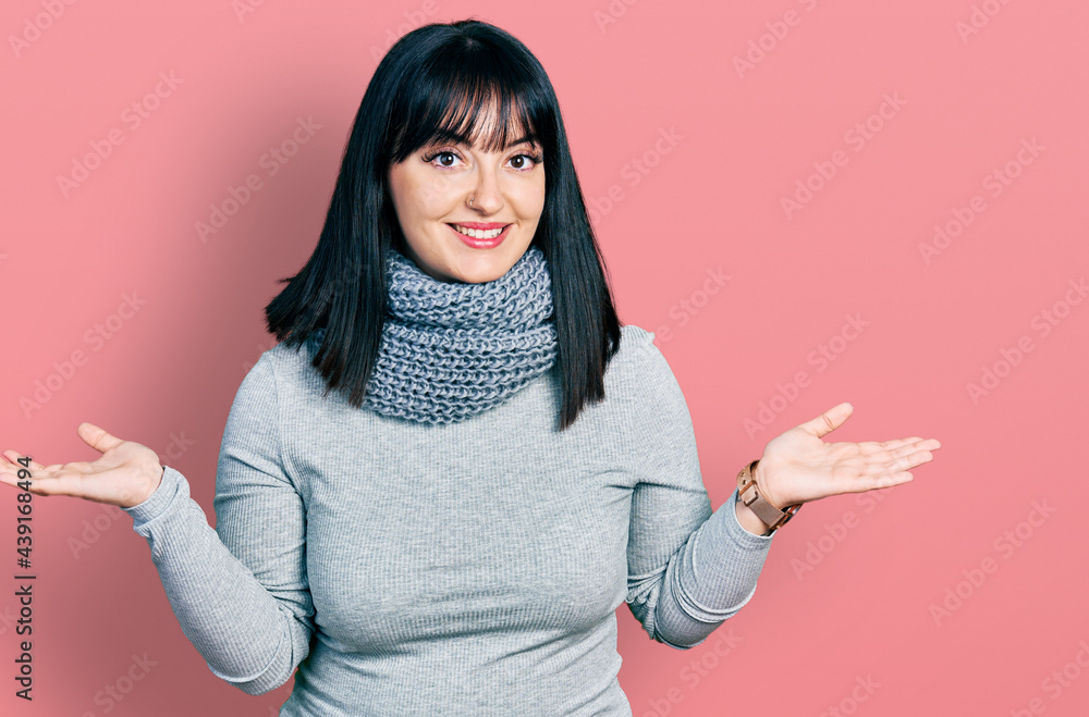 Young hispanic plus size woman wearing winter scarf smiling showing both hands open palms, presenting and advertising comparison and balance Young hispanic plus size woman wearing winter scarf smiling showing both hands open palms, presenting and advertising comparison and balance