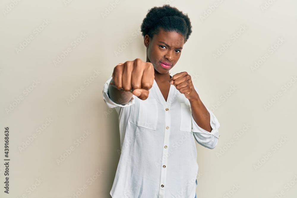 Young african american girl wearing casual clothes punching fist to fight, aggressive and angry attack, threat and violence