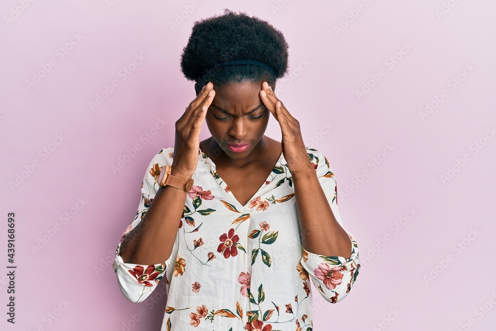 Young african american girl wearing casual clothes with hand on head for pain in head because stress. suffering migraine. Young african american girl wearing casual clothes with hand on head for pain in head because stress. suffering migraine.
