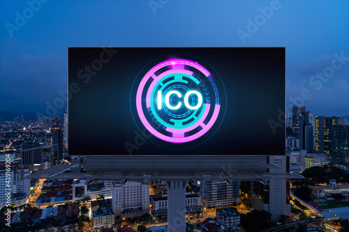 ICO hologram icon on billboard over panorama city view of Kuala Lumpur at night. KL is the hub of blockchain projects in Malaysia, Asia. The concept of initial coin offering, decentralized finance