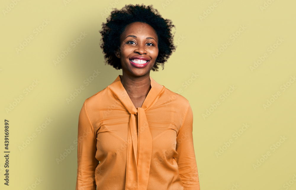 Fototapeta premium African american woman with afro hair wearing elegant shirt looking positive and happy standing and smiling with a confident smile showing teeth