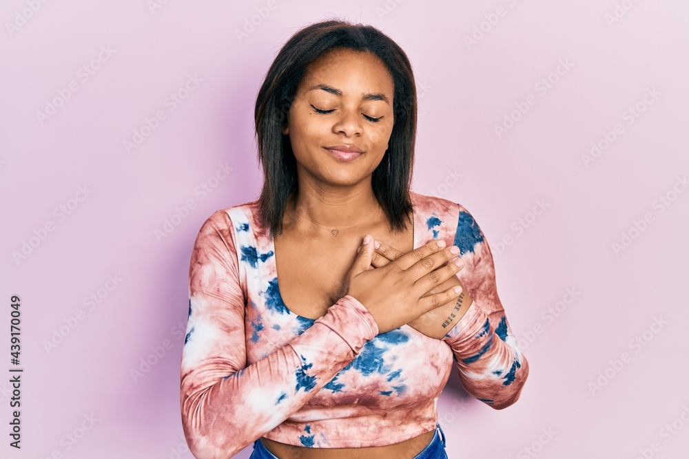 Young african american girl wearing casual clothes smiling with hands on chest with closed eyes and grateful gesture on face. health concept.