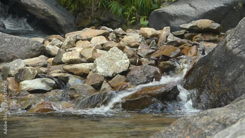 A pristine flowing water on beautiful rocks in a waterfall in Malaysia A pristine flowing water on beautiful rocks in a waterfall in Malaysia