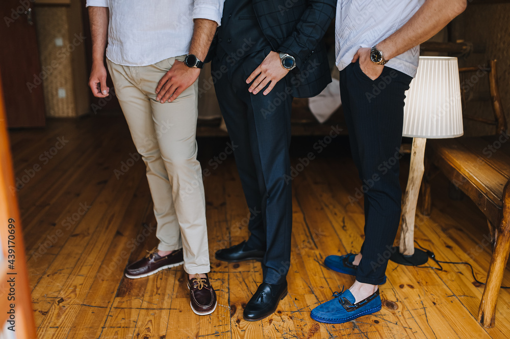 Several gentlemen, businessmen men stand in the office on the wooden floor, showing watches, shoes. Working environment. Photography, concept.