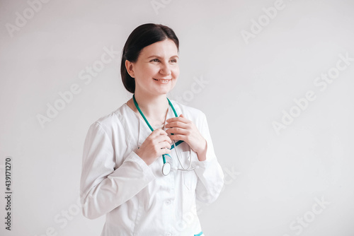 Friendly woman doctor with a stethoscope and coat on a white background. Copy, empty space for text