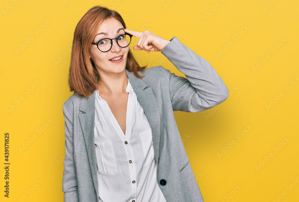 Young caucasian woman wearing business style and glasses smiling pointing to head with one finger, great idea or thought, good memory