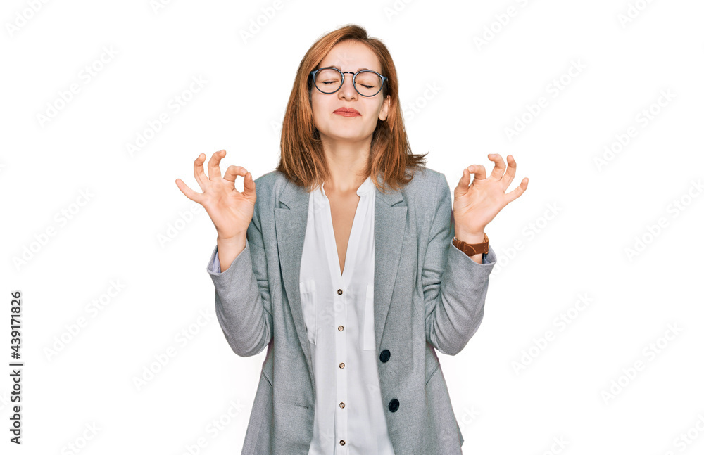 Young caucasian woman wearing business style and glasses relaxed and smiling with eyes closed doing meditation gesture with fingers. yoga concept. Young caucasian woman wearing business style and glasses relaxed and smiling with eyes closed doing meditation gesture with fingers. yoga concept.