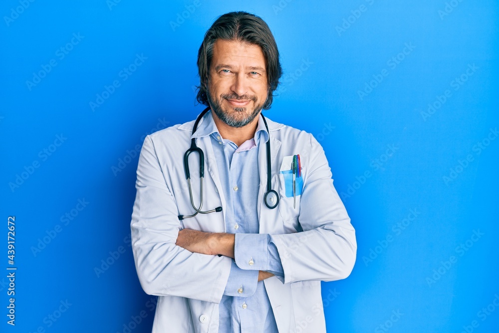 Middle age handsome man wearing doctor uniform and stethoscope happy face smiling with crossed arms looking at the camera. positive person. Middle age handsome man wearing doctor uniform and stethoscope happy face smiling with crossed arms looking at the camera. positive person.