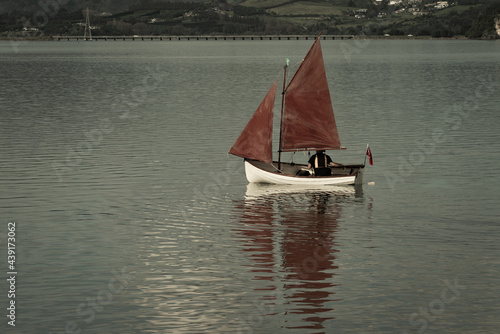 Traditional style red sails on small yacht becalmed in bay. photo