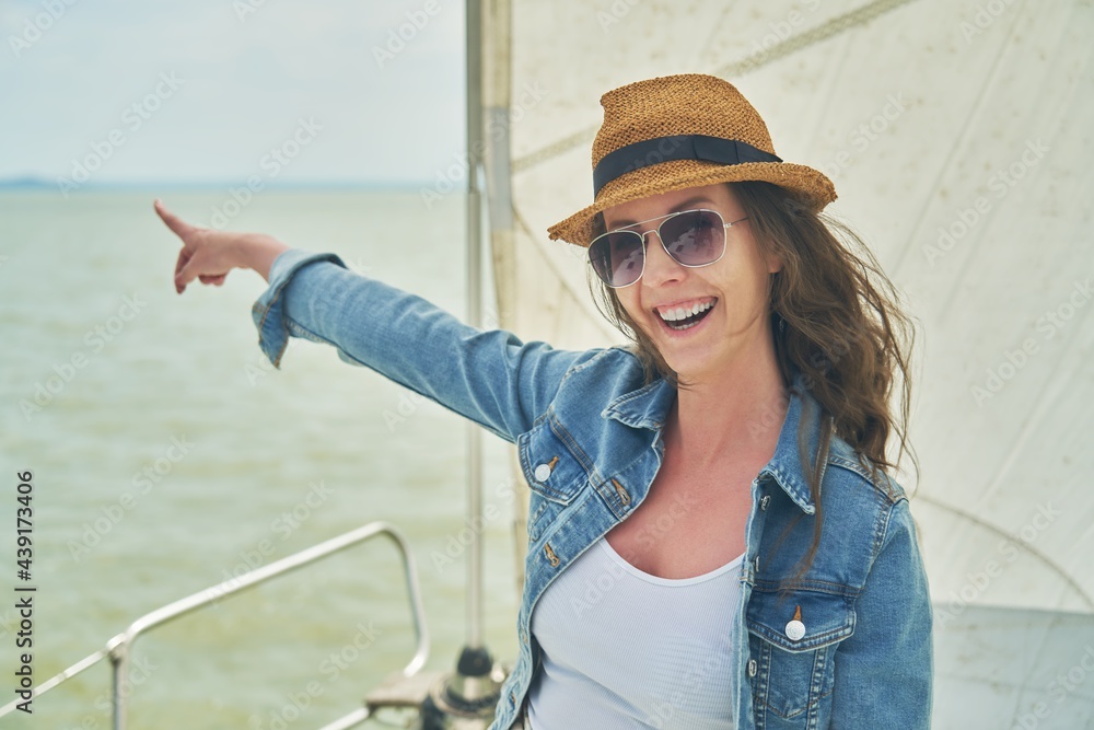 Happy young woman enjoying cruising on sailboat on a sunny cloudy summer day.