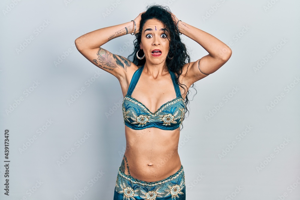 Obraz premium Young woman wearing bindi and traditional belly dance clothes crazy and scared with hands on head, afraid and surprised of shock with open mouth