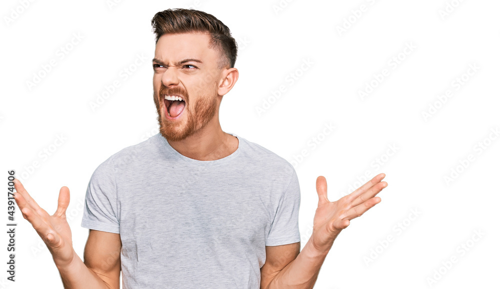 Young redhead man wearing casual grey t shirt crazy and mad shouting and yelling with aggressive expression and arms raised. frustration concept. Young redhead man wearing casual grey t shirt crazy and mad shouting and yelling with aggressive expression and arms raised. frustration concept.