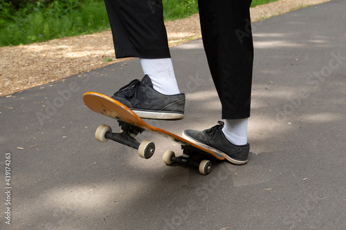 A young man rides a skateboard in the park in the summer.