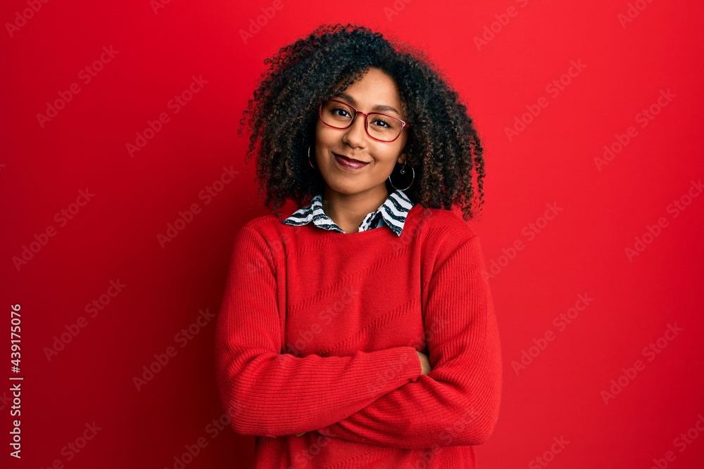 Beautiful african american woman with afro hair wearing sweater and glasses happy face smiling with crossed arms looking at the camera. positive person. Beautiful african american woman with afro hair wearing sweater and glasses happy face smiling with crossed arms looking at the camera. positive person.