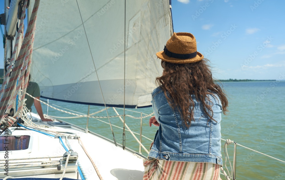 Fototapeta premium Happy young woman sailing, enjoying cruising on sailboat on a sunny summer day.