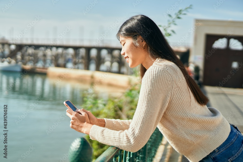Young asian woman smiling happy using smartphone at the city.