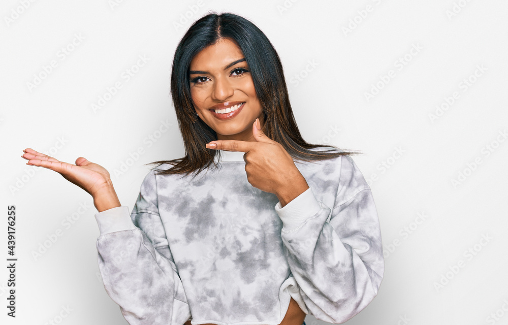 Young latin transsexual transgender woman wearing casual clothes amazed and smiling to the camera while presenting with hand and pointing with finger. Young latin transsexual transgender woman wearing casual clothes amazed and smiling to the camera while presenting with hand and pointing with finger.