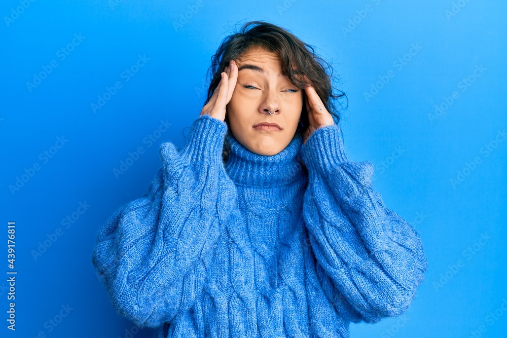 Young hispanic woman wearing casual winter sweater with hand on head, headache because stress. suffering migraine. Young hispanic woman wearing casual winter sweater with hand on head, headache because stress. suffering migraine.