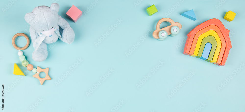 Baby kids toy for children with teddy bear, wooden rainbow house, car, organic teether, colorful blocks on light blue background. Top view, flat lay Baby kids toy for children with teddy bear, wooden rainbow house, car, organic teether, colorful blocks on light blue background. Top view, flat lay
