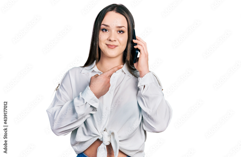 Young hispanic woman having conversation talking on the smartphone smiling happy pointing with hand and finger Young hispanic woman having conversation talking on the smartphone smiling happy pointing with hand and finger