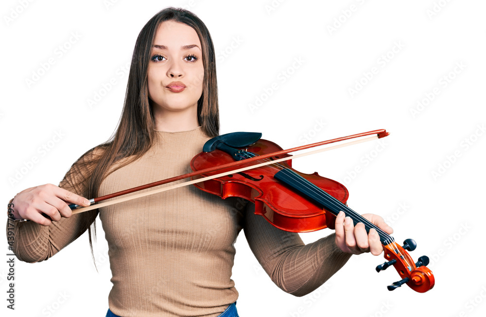Young hispanic girl playing violin looking at the camera blowing a kiss being lovely and sexy. love expression. Young hispanic girl playing violin looking at the camera blowing a kiss being lovely and sexy. love expression.