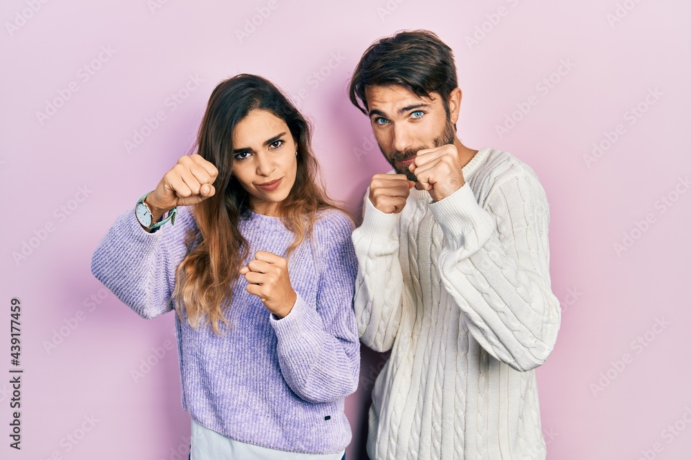 Young hispanic couple wearing casual clothes punching fist to fight, aggressive and angry attack, threat and violence Young hispanic couple wearing casual clothes punching fist to fight, aggressive and angry attack, threat and violence