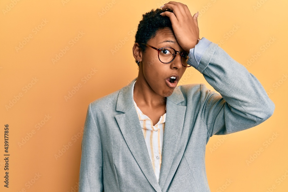 Young african american girl wearing business jacket and glasses surprised with hand on head for mistake, remember error. forgot, bad memory concept. Young african american girl wearing business jacket and glasses surprised with hand on head for mistake, remember error. forgot, bad memory concept.