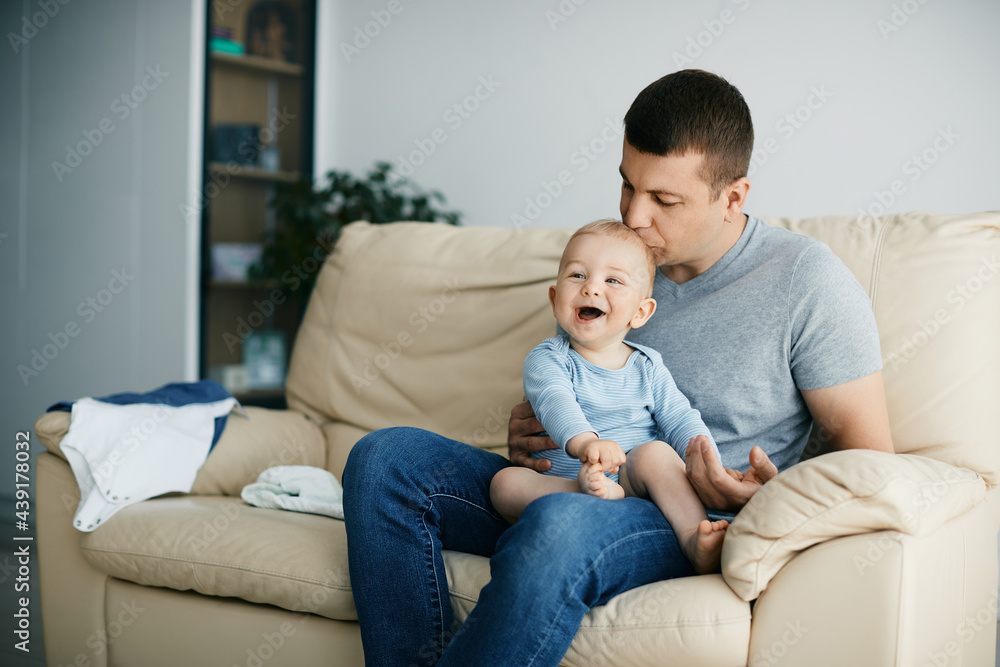 Joyful baby laughing while father is kissing him at home. Joyful baby laughing while father is kissing him at home.