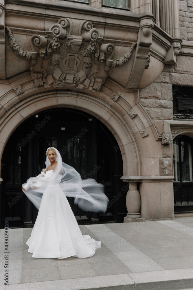 the bride with a fluttering veil stands on the street