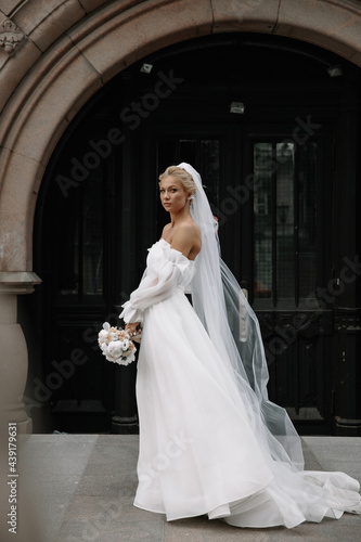 the bride is standing on the street with a bouquet of flowers