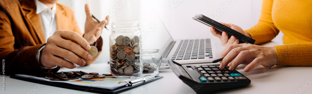 businessman holding coins putting in glass and using calculator. concept saving money and finance accounting.