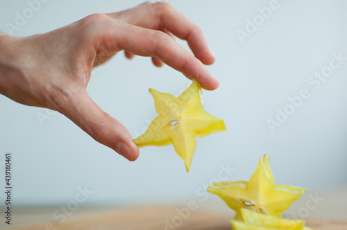 Female hands are holding slice of exotic ripe starfruit or averrhoa carambola. Healthy food, fresh organic star apple fruit