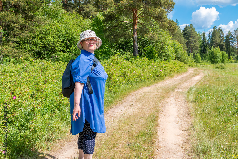 Grandmother goes on a hike. An elderly woman on a walk in nature.