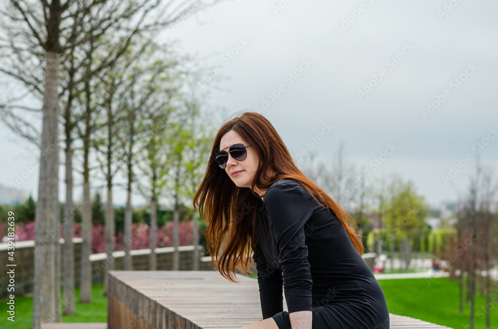 beautiful beautiful young white girl in sunglasses sitting in the park