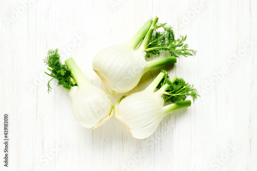 Fresh Florence fennel bulbs on white wooden background. Raw organic spring vegetables top view. Genuine healthy eating.