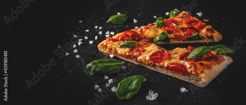two slice of flatbread Pizza with Mozzarella cheese, Tomatoes, pepper, Spices and Fresh Basil. Italian pizza. Pizza Margherita or Margarita  on Dark grey black slate background
