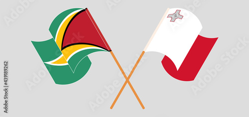 Crossed and waving flags of Guyana and Malta