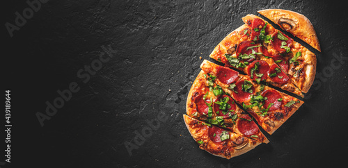 flatbread Pepperoni Pizza with Mozzarella cheese, salami, Tomato sauce, pepper, Spices. Italian pizza on Dark grey black slate background