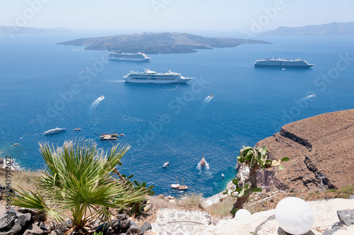 Aerial panoramic view of the caldera of the volcano on the island of Santorini with cruise ships. In the background the blue sky and the Aegean Sea