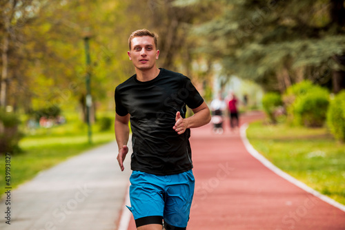Runners training, young male running exercising concentrated on road in beautiful nature